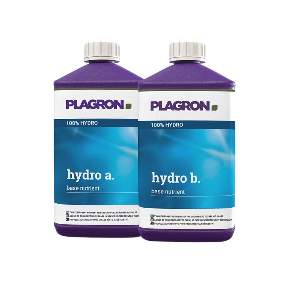 Sobre um fundo branco estão representadas duas garrafas de plástico Plagron Hydro A + B de Bertels B.V., fertilizante de dois componentes para a fase de floração, para substratos inertes, com tampas violetas e etiquetas azul-branco.