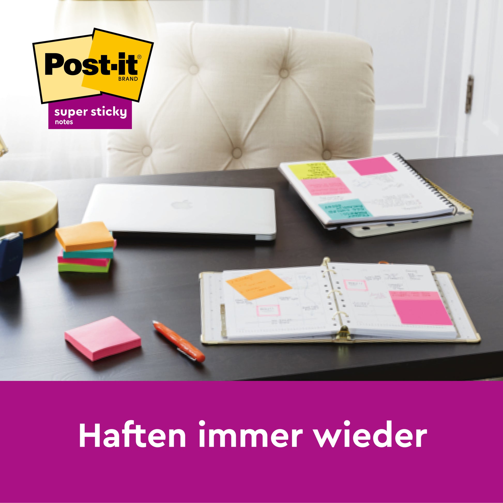 Ein schwarzer Schreibtisch mit geschlossenem Laptop, offenen Planern mit bunten Haftnotizen, Stapeln von 3M Deutschland GmbH Post-It® Super Sticky Notes (47,6 mm x 47,6 mm, 45 Blatt/Block, 4 Blöcke), Stift, Lampe, Stuhl und dem Logo mit "Haften immer wieder".