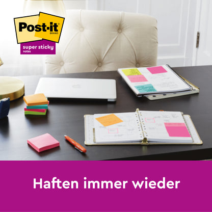Ein Schreibtisch mit einem 3M Post-it® Z-Notes Dispenser PRO in Schwarz und gelben Post-it® Super Sticky Z-Notes (76x76mm, 90 Blatt), dazu ein Planer, ein Notizbuch, ein geschlossener Laptop, ein Stift und eine Lampe. Das Post-it Markenlogo erscheint oben links. Text: "Haften immer wieder.