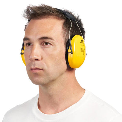 Um homem com cabelo castanho curto usa um protetor auricular 3M™ PELTOR™ Optime™ I H510A (SNR 27 dB) da 3M Deutschland GmbH e uma camisa branca simples. Ele olha para frente em um fundo totalmente branco.