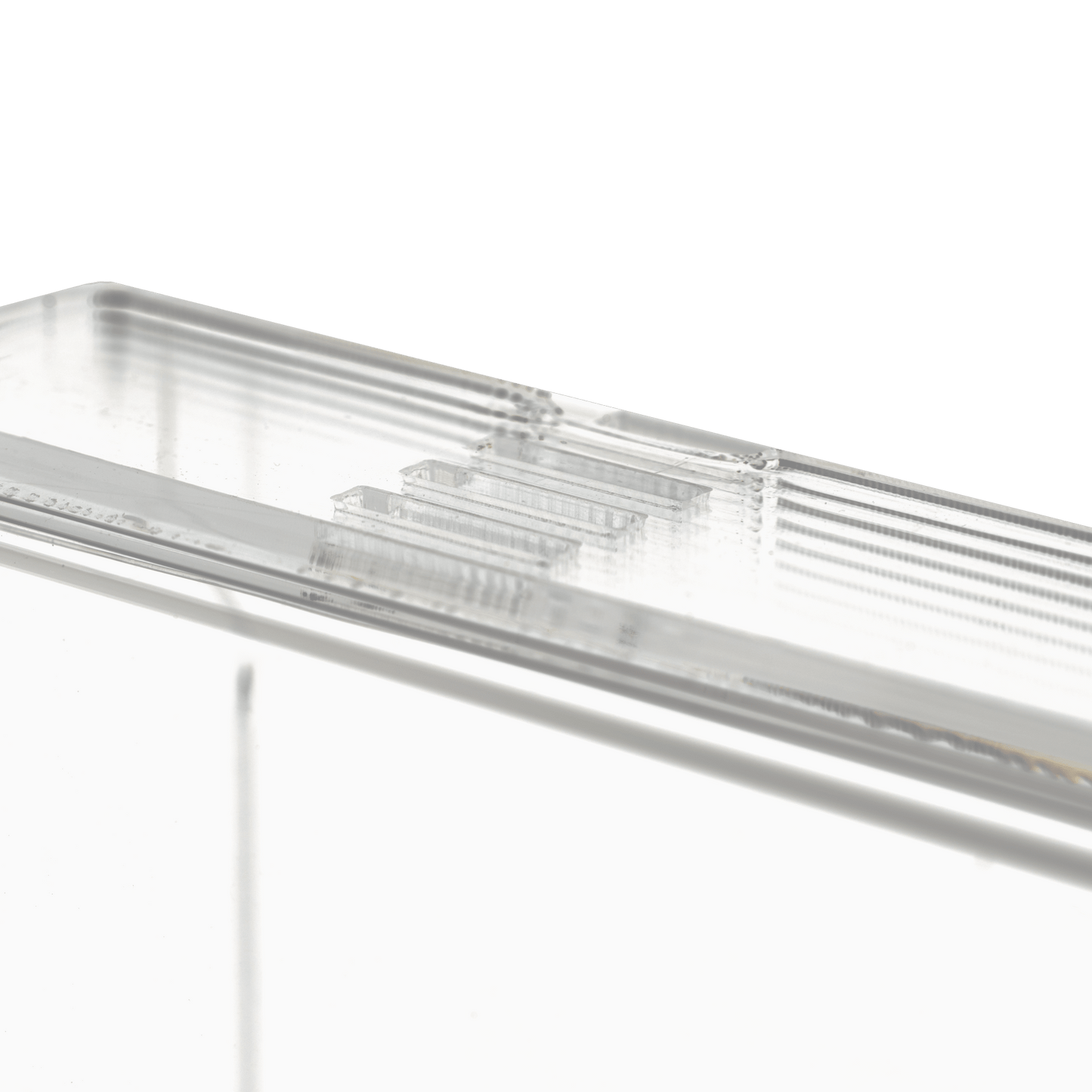 Close-up do dispensador de luvas descartáveis transparente e leitoso (250 x 135 x 55-90 mm) da AMPri Handelsgesellschaft mbH, um suporte de dispenser retangular de acrílico com bordas estriadas sobre um fundo branco sólido.