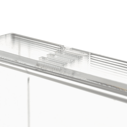 Close-up do dispensador de luvas descartáveis transparente e leitoso (250 x 135 x 55-90 mm) da AMPri Handelsgesellschaft mbH, um suporte de dispenser retangular de acrílico com bordas estriadas sobre um fundo branco sólido.