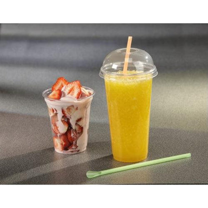 Um copo transparente com parfait de morango, morangos fatiados e iogurte está ao lado de um copo alto de smoothie Starpak feito de PET transparente com uma tampa em domo Starpak 50 "Hurricane" (redonda, Ø 9,5 cm – 4,5 cm); sobre a superfície cinza há uma vareta verde para mexer.