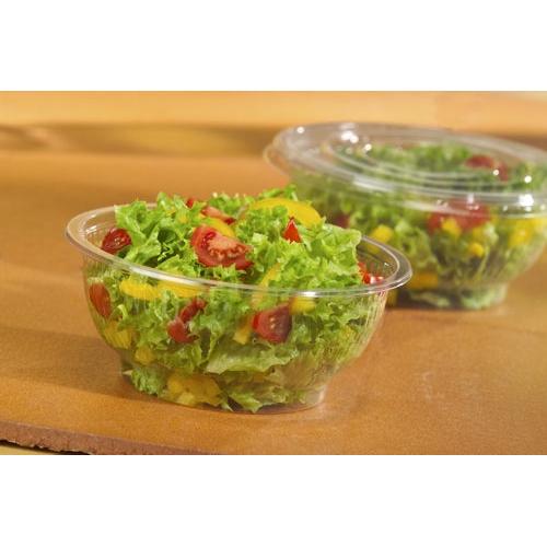 Uma tampa Starpak 50 para tigelas de salada, R-PET redonda Ø 18 cm, clara, cobre uma salada de folhas verdes, tomates cereja e pimentos amarelos sobre um fundo castanho. No fundo, pode-se ver outro recipiente de salada Starpak em R-PET transparente.