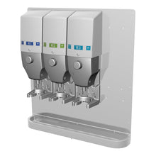 Três dispensadores do sistema DQFM (azul, verde, azul), montados na parede com uma bandeja de gotejamento de metal, pré-instalados para baixo fluxo. Compatível com concentrado elevado para uso higiênico. Marca: Diversey Deutschland GmbH & Co. OHG.