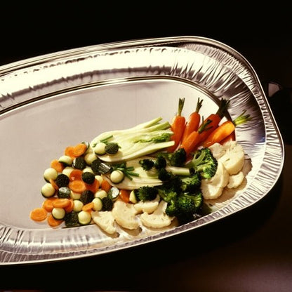 Uma travessa de servir Starpak 10 oval de alumínio apresenta uma seleção colorida de cenouras baby cozidas, brócolis, couve-flor, abobrinha e beterrabas – ideal para buffets e catering ou festas de casamento contra um fundo escuro.