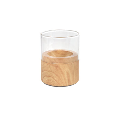 Der Duni GmbH Kerzenhalter Glas Neat 70 x 61 mm ist ein klarer Glasbecher in einem runden Holzsockel mit natürlicher Oberfläche, der ein elegantes Wohnaccessoire vor weißem Hintergrund darstellt.
