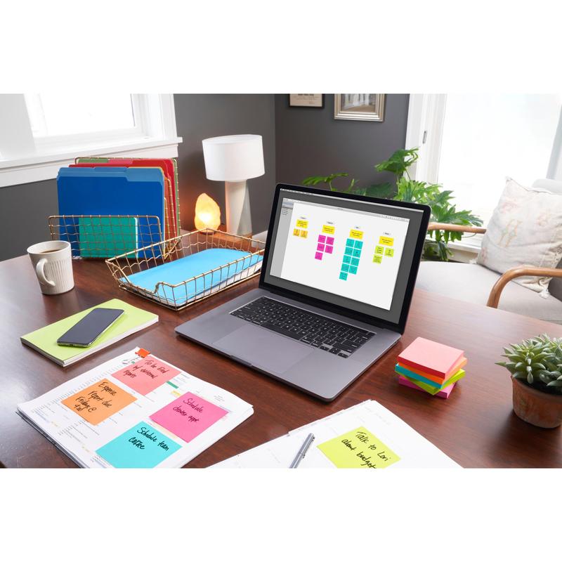 Uma mesa com um laptop, sobre a qual um organizador de notas adesivas, notas Post-it® (76 mm x 76 mm, 100 folhas/bloco, 100% PEFC) da 3M Deutschland GmbH, pastas, papelada, um telefone, uma lâmpada, uma planta e luz solar iluminam a área de trabalho organizada.