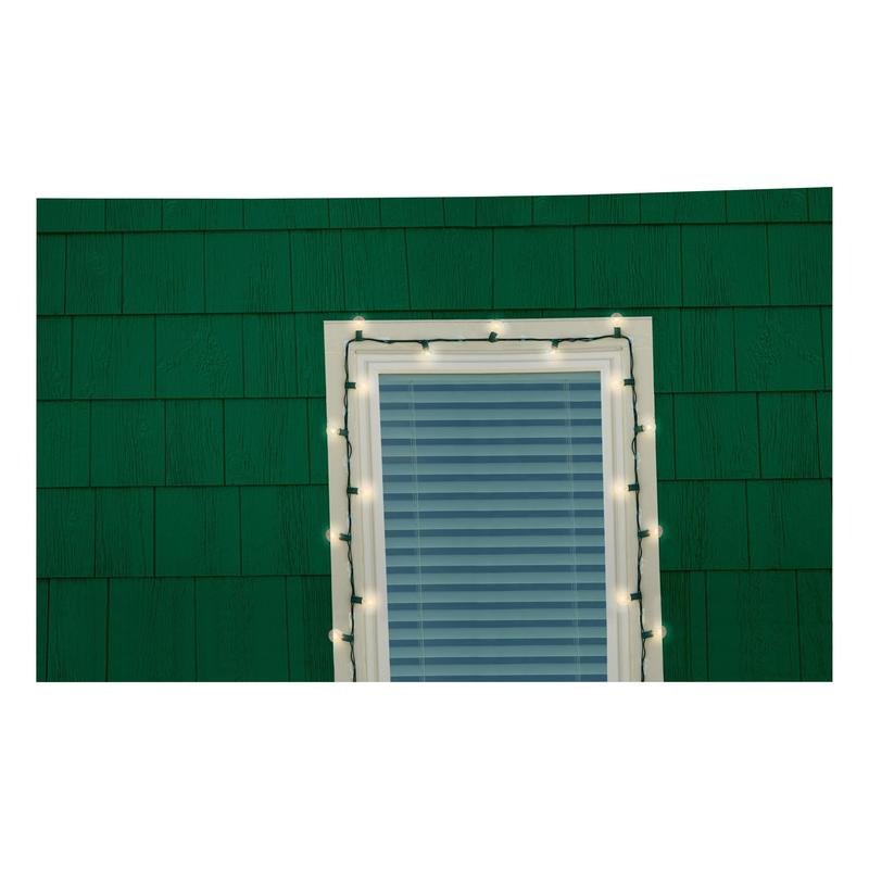 Uma janela com persianas fechadas em uma parede de telhas verdes é contornada por luzes brancas, que foram fixadas com segurança usando os clipes de luzes externas 3M Command™ (17017CLR-AWPU) da 3M Deutschland GmbH para uma instalação confiável da iluminação exterior.