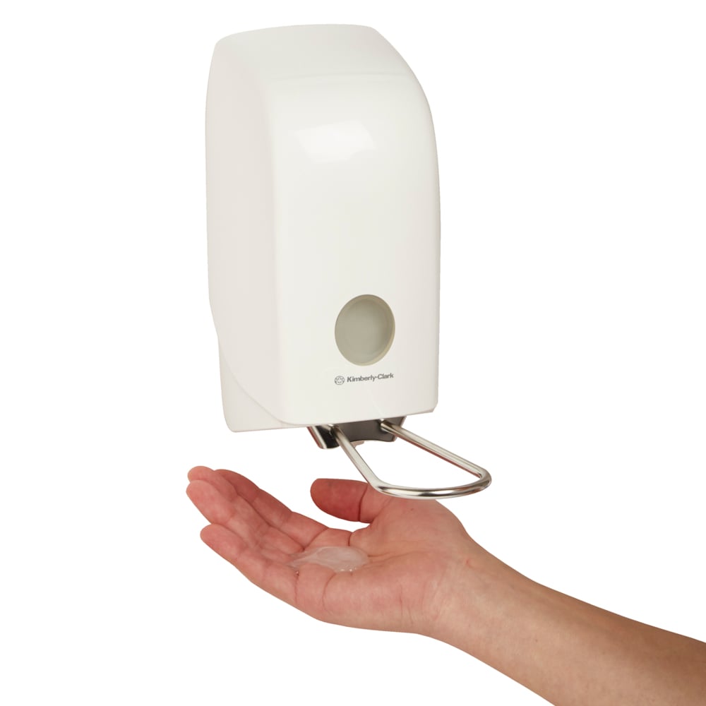 Uma mão é colocada sob o dispensador montado na parede Aquarius™ para loções de lavagem (branco, 1 Ltr) da Kimberly-Clark GmbH, que dispensa o líquido para uma aplicação fácil e higiênica na palma da mão.
