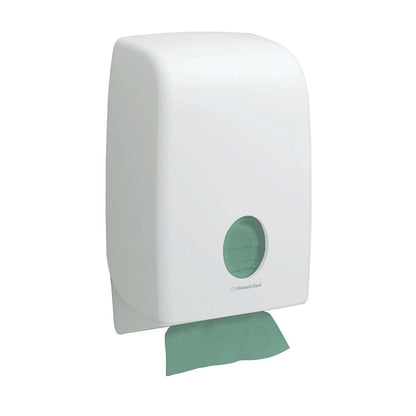 Um dispensador de parede branco com janela circular exibe toalhas Hostess™ NATURA™ dobragem em ziguezague da Kimberly-Clark GmbH (23 x 25 cm); uma toalha ecológica é parcialmente dispensada na parte inferior.