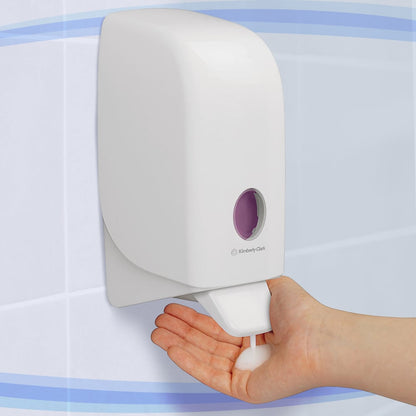 Uma pessoa dispensa sabão em espuma de um dispensador branco Aquarius™ para loções de lavagem - cartucho / 1 Ltr da Kimberly-Clark GmbH em sua mão em um banheiro revestido de azulejos.