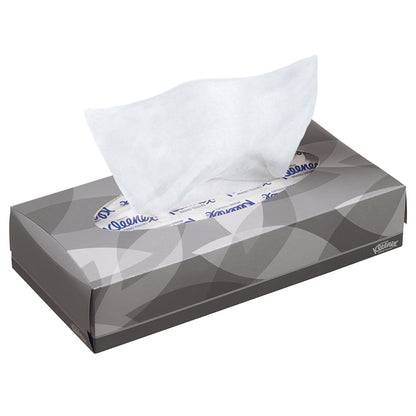 Uma caixa retangular cinza com lenços de cosméticos Kleenex® - Standard / Branco da Kimberly-Clark GmbH, de onde é puxado um único lenço branco. Padrão sutil de folhas e texto da marca. Ideal para remoção de maquiagem ou limpeza facial.