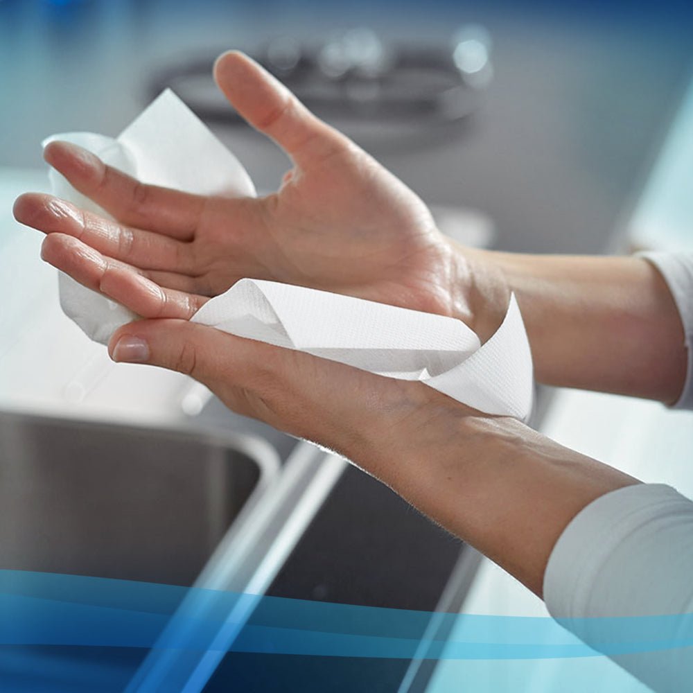Uma pessoa usa uma toalha de papel branca Scott® - MultiFold (Kimberly-Clark GmbH, 16 clipes x 250 folhas) sobre uma pia em uma cozinha moderna para secagem higiênica das mãos.