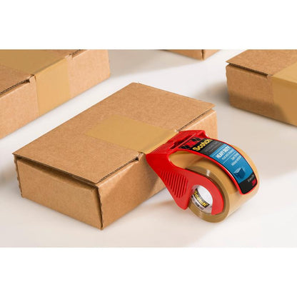 Uma fita adesiva de embalagem extra forte Scotch® da 3M Deutschland GmbH, castanho (48 mm x 20,3 m), no dispensador manual vermelho, fecha uma caixa; outras caixas seladas estão ao lado sobre uma superfície branca.