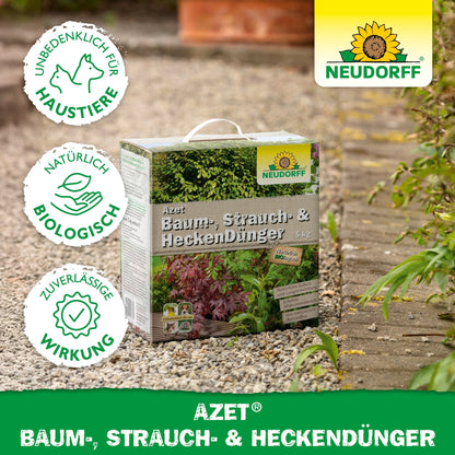 Uma caixa de 5 kg de Fertilizante para Árvores, Arbustos e Sebes Azet da Neudorff Shop está ao ar livre no solo do jardim. A imagem mostra os logotipos de proteção animal, ingredientes biológicos e efeito confiável, bem como uma marca clara da Neudorff. Ideal para arbustos e árvores.