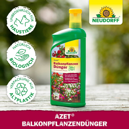 Em uma mesa está uma garrafa do Neudorff Shop Azet Fertilizante Líquido para Plantas de Varanda com símbolos para animais de estimação, orgânico e bioplástico; ao fundo, flores de verão florescendo, caixas de varanda e o logotipo da Neudorff.