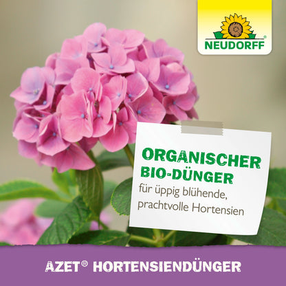 Rosa Hortensie mit grünen Blättern. Auf einem Etikett steht "Organischer Spezialdünger für üppig blühende, prachtvolle Hortensien". Neudorff Shop-Logo (Sonnenblume) oben rechts. Text unten: "Azet HortensienDünger flüssig.
