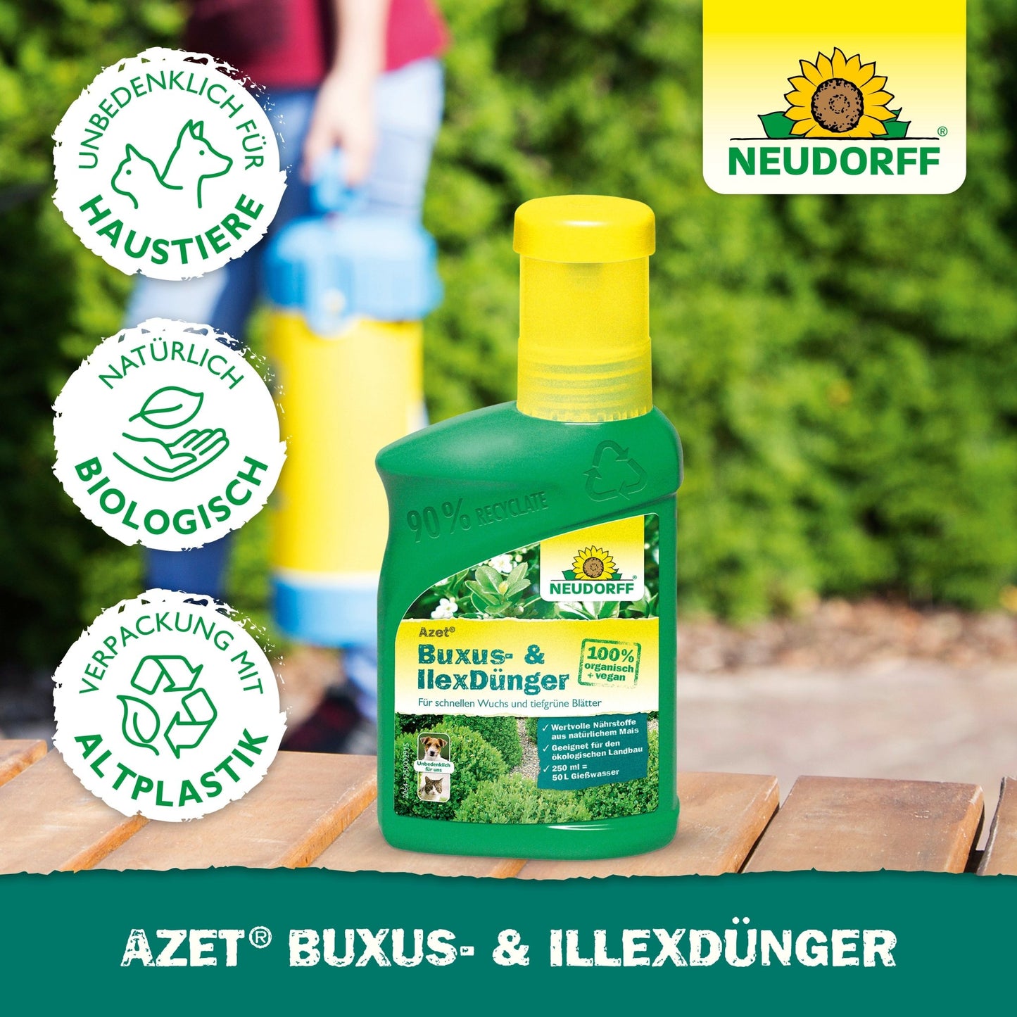 Uma garrafa verde de Neudorff Shop Azet Buxus- & IlexDünger líquido está sobre uma superfície de madeira ao ar livre. Ícones mostram a segurança para animais de estimação, ingredientes biológicos e embalagens recicladas. O logotipo da Neudorff aparece no canto superior direito.