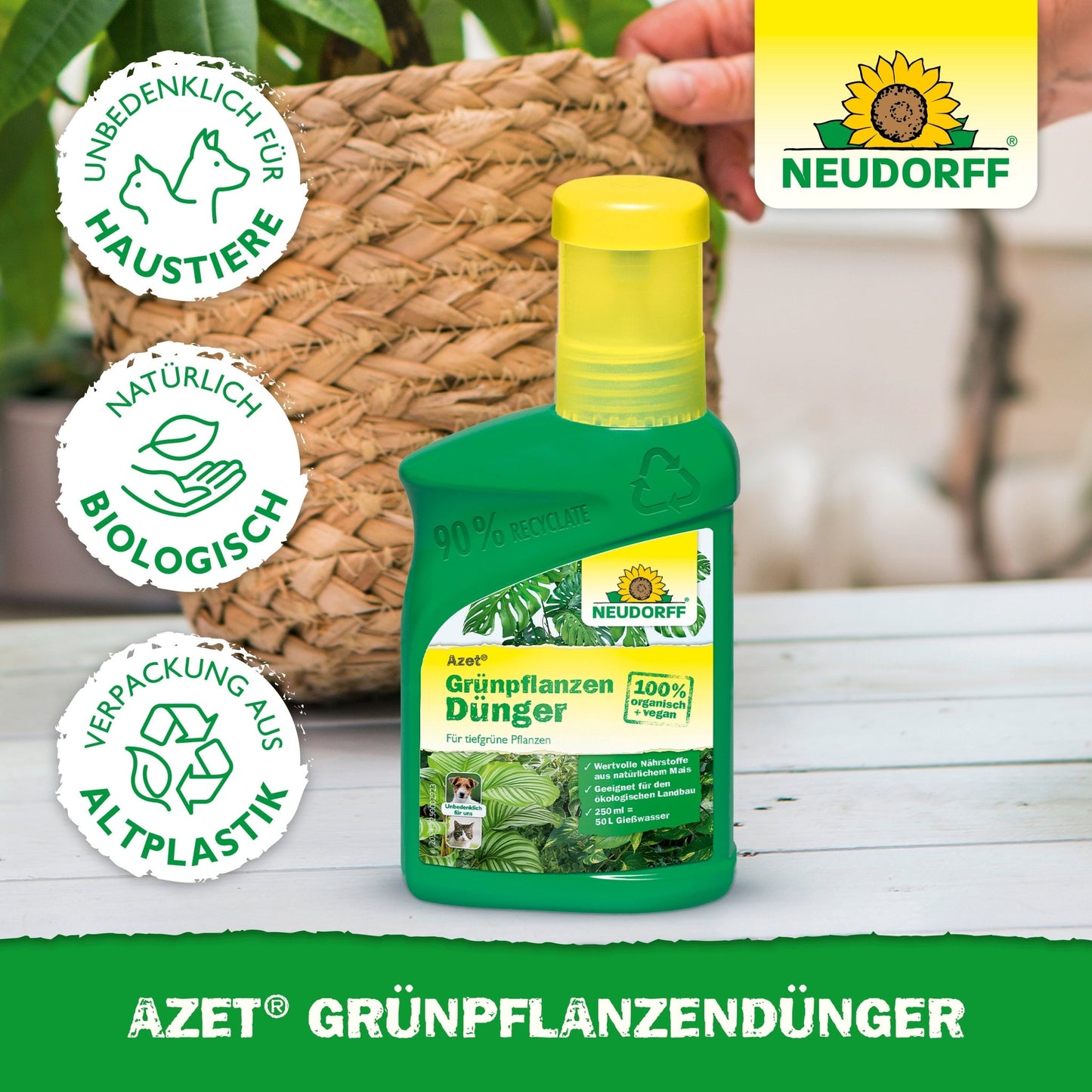 Uma garrafa verde da Neudorff Shop Azet GrünpflanzenDünger líquido está em uma mesa ao lado de uma planta em vaso. No rótulo estão os nutrientes para plantas verdes, segurança para animais de estimação, ingredientes naturais e embalagens recicladas. Ao fundo, vê-se uma mão.
