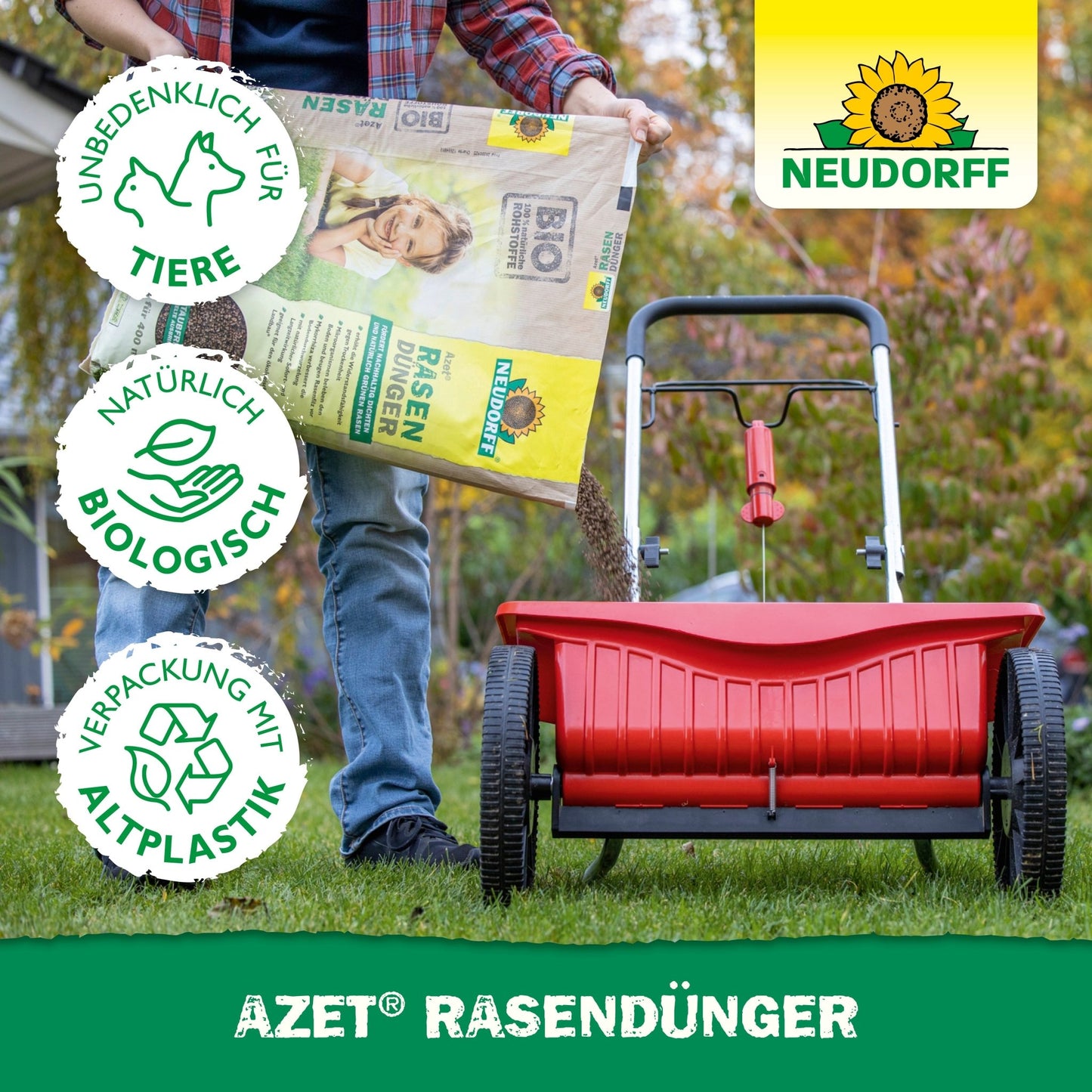 Uma pessoa enche um espalhador vermelho com Neudorff Shop Azet RasenDünger 2,5-5 kg, para promover áreas de relva densas. Três símbolos indicam que é amigo dos animais, biologicamente natural e feito de plástico reciclado. O logotipo Neudorff é visível.