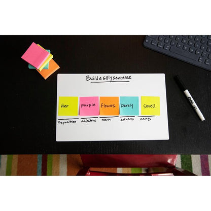 Um bloco de notas Post-it® da 3M Deutschland GmbH (76x76mm, 450 folhas, 100% PEFC) mostra uma tarefa de construção de frases em um quadro branco com etiquetas gramaticais; notas adesivas adicionais, um marcador, um teclado e um tapete listrado estão por perto.
