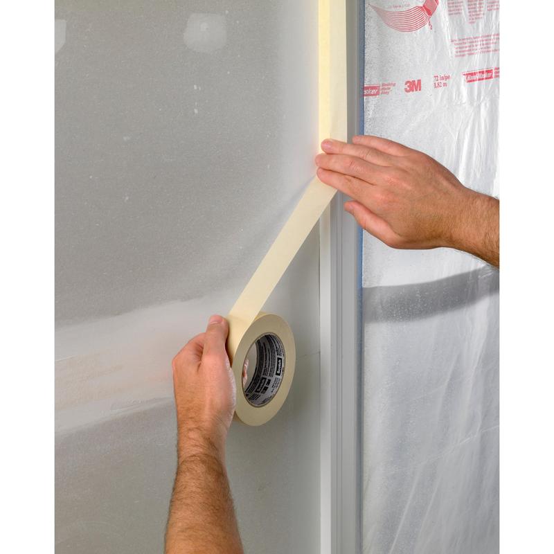 Uma pessoa aplica fita adesiva Scotch® Abdeckband Basic, 50 m da 3M Deutschland GmbH ao longo da borda de uma moldura de janela revestida de plástico, provavelmente como preparação para pintura ou trabalhos de construção.