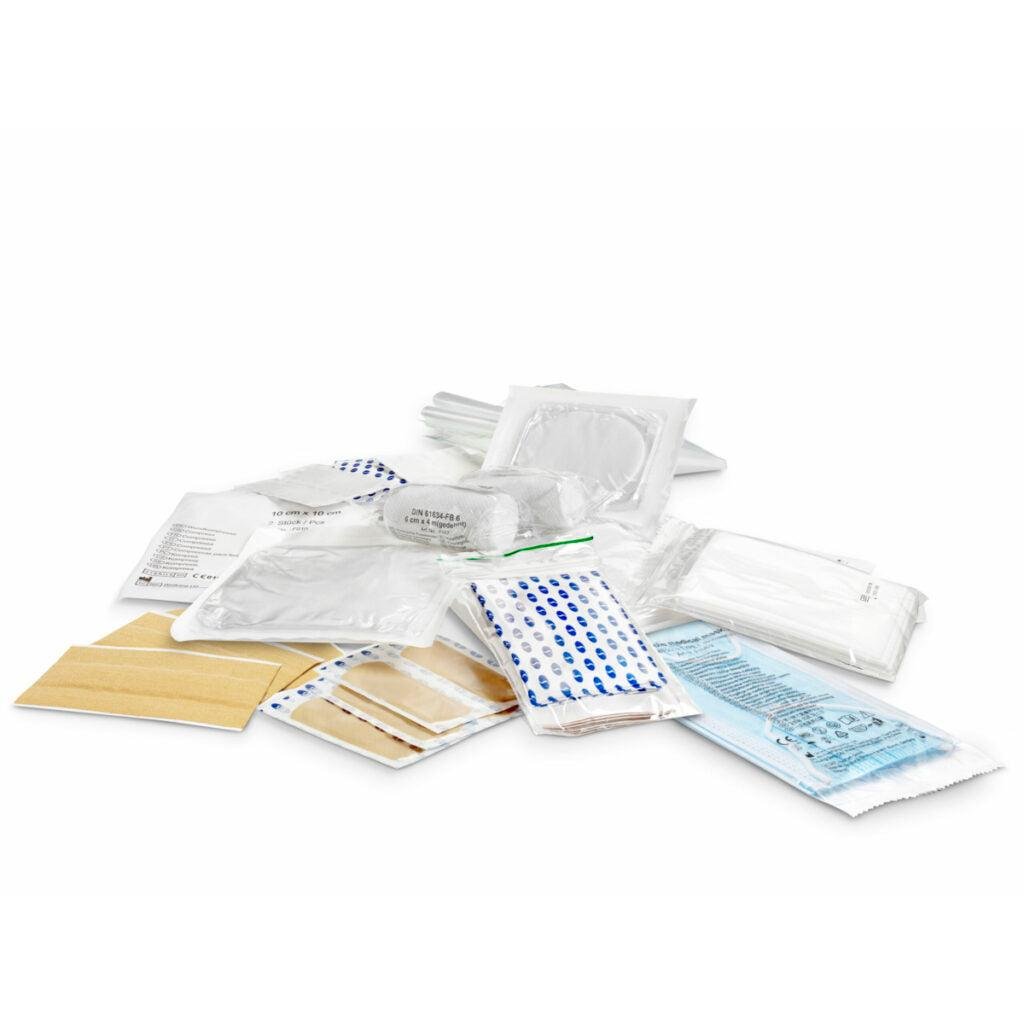 Curativos médicos estéreis, ataduras e gazes do conjunto DIN-Mine | Embalagem (1 peça) da Orkla Wound Care AB estão organizados em embalagens individuais sobre uma superfície branca e refletem a precisão organizada dos artigos de papelaria DIN-Mine.