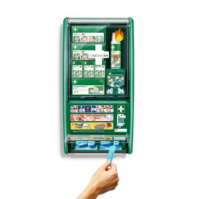 Uma estação de primeiros socorros e queimaduras Cederroth verde da Orkla Wound Care AB está montada em uma parede branca, equipada com curativos, gel para queimaduras, lavagem ocular e mais. Uma mão puxa uma fita adesiva azul do dispensador inferior da caixa de 1 unidade.
