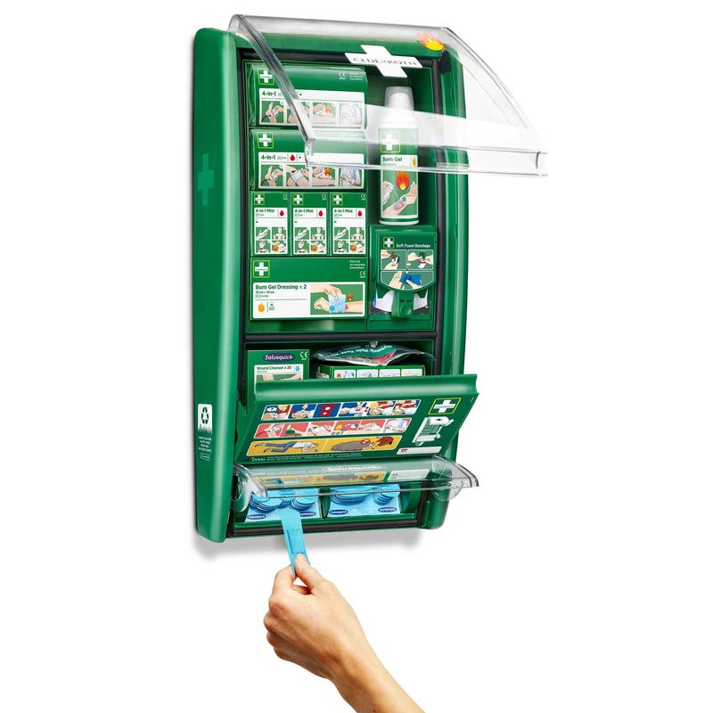 A estação de primeiros socorros e queimaduras Cederroth da Orkla Wound Care AB é um conjunto verde montado na parede com compartimentos rotulados para bandagens, curativos e gel para queimaduras. Uma mão puxa um pano azul da unidade aberta, revelando suprimentos organizados e instruções claras.