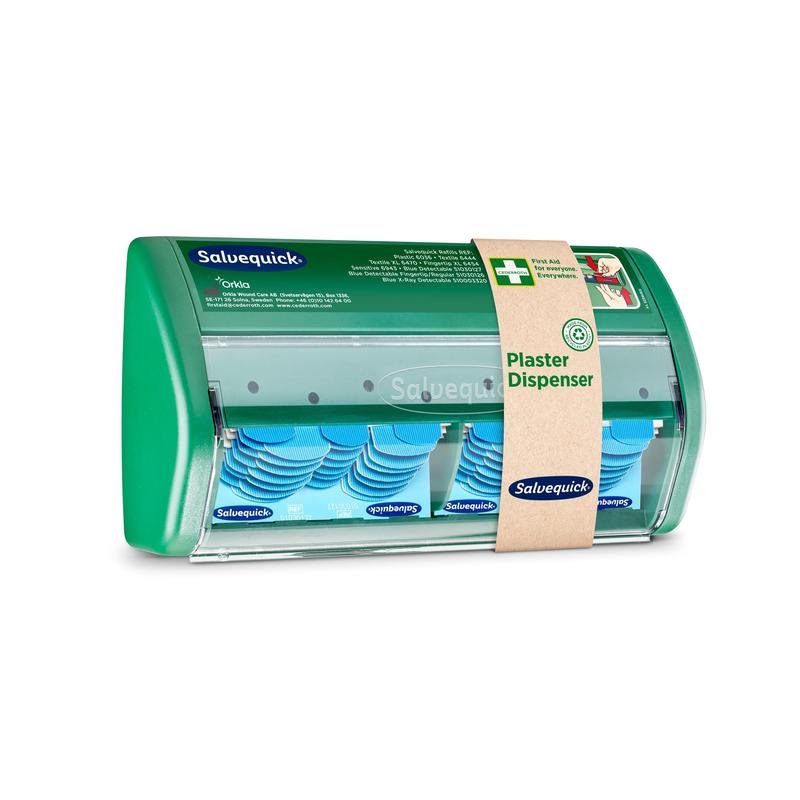 Um dispensador de pensos Salvequick da Orkla Wound Care AB tem uma frente transparente e dispensa pensos azuis detectáveis; uma faixa de papel castanho identifica-o como dispensador de pensos".