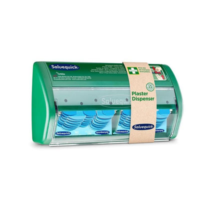 Um dispensador de pensos Salvequick da Orkla Wound Care AB tem uma frente transparente e dispensa pensos azuis detectáveis; uma faixa de papel castanho identifica-o como dispensador de pensos".