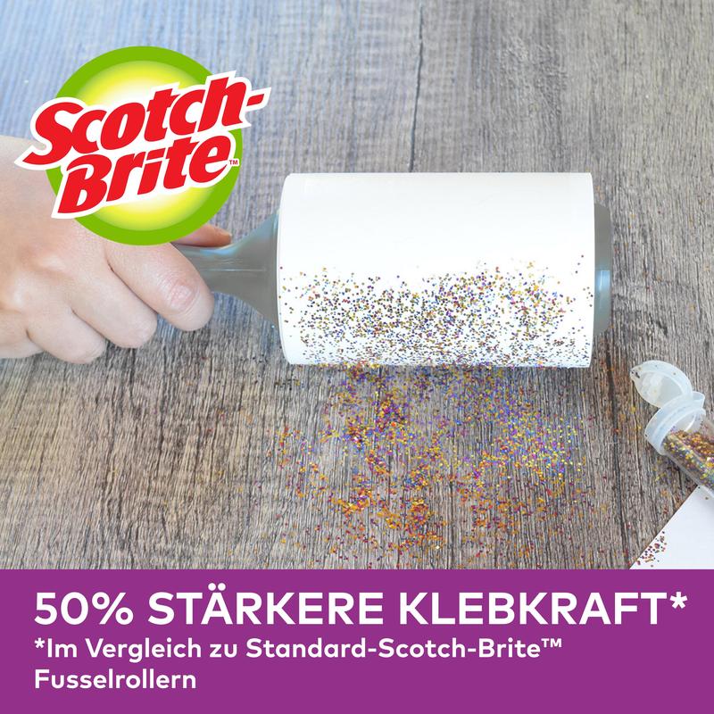 Uma mão utiliza o rolo Scotch-Brite™ Pet Extra Sticky* para pêlos de animais da 3M Deutschland GmbH (48 folhas) para remover glitter derramado numa superfície de madeira. Publicidade alemã: 50% mais aderente do que modelos padrão.