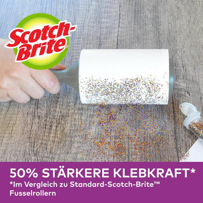Uma mão utiliza o rolo Scotch-Brite™ Pet Extra Sticky* para pêlos de animais da 3M Deutschland GmbH (48 folhas) para remover glitter derramado numa superfície de madeira. Publicidade alemã: 50% mais aderente do que modelos padrão.