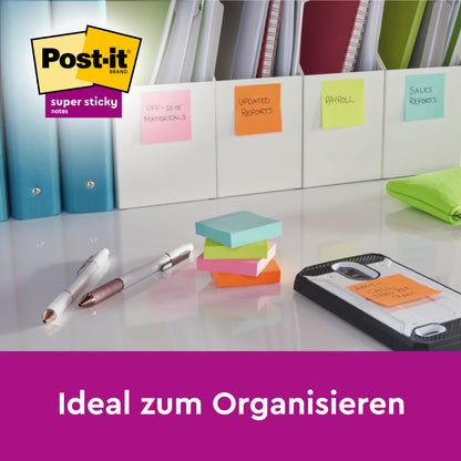 Ein Schreibtisch zeigt Ordner, die mit bunten Post-it® Super Sticky Z-Notes (76x76 mm, 3M Deutschland GmbH), Stiften, einem Smartphone, einem grünen Tuch und dem Post-it-Logo organisiert sind. Das Set enthält 20 Blöcke + 4 kostenlose, 100% PEFC-zertifiziert, in einer Kartonverpackung.