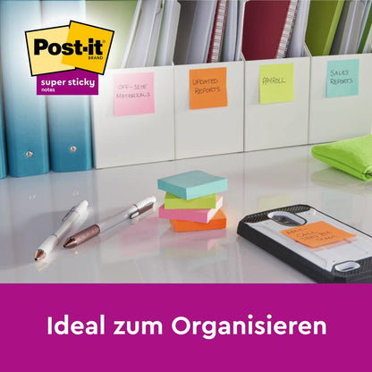 Uma mesa com pastas, etiquetadas com Notas Adesivas Super Sticky Post-it® (várias cores, 76x76 mm, 45 folhas/bloco, 3 blocos, 100% PEFC) da 3M Deutschland GmbH, além de canetas, pano verde, smartphone em prancheta. Texto: "Ideal para organização."