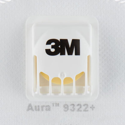 O close-up de uma máscara de partículas branca 3M™ Aura™ Comfort Cool Flow™ 9322+, FFP2, com válvula da 3M Deutschland GmbH mostra o logotipo 3M preto, a válvula de plástico ventilada e parte da designação do modelo abaixo da válvula.