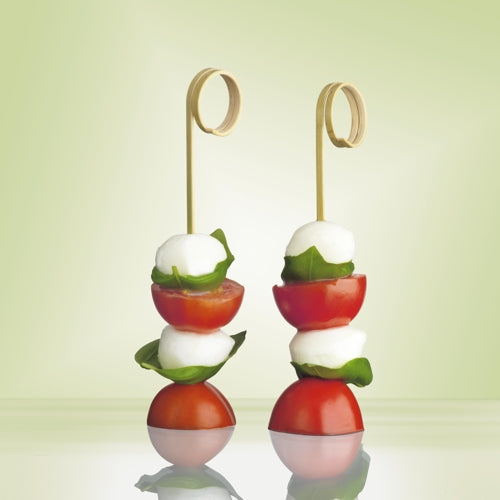 Dois PAPSTAR 100 palitos de finger food "pure" da PAPSTAR GmbH feitos de plástico de alta qualidade seguram bolas de mozzarella, manjericão e tomates cereja, decorativamente em um fundo verde suave – ideal para festas e eventos.