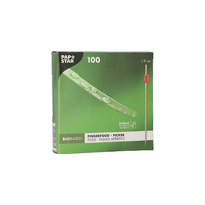 A caixa verde "PAPSTAR 100 palitos de Fingerfood" da PAPSTAR GmbH contém 100 palitos de bambu com um comprimento de 9 cm cada. A embalagem de base biológica mostra um palito com ponta vermelha, ideal para servir espetos de fingerfood em qualquer evento.