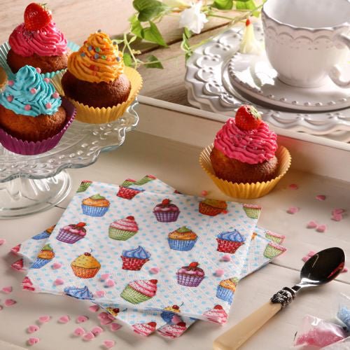 Uma mesa está posta com cupcakes em um suporte de vidro, um prato, colher, xícara de chá branca e pires, granulados em forma de coração rosa e coloridos PAPSTAR 20 guardanapos 33x33cm 3-camadas 1/4-dobra design conjunto 5 da PAPSTAR GmbH.