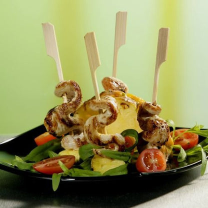 PAPSTAR espetos de churrasco de 21 cm "Golf" da PAPSTAR GmbH: Espetos perfeitos para churrascos e festas de grelhados com frango e ananás sobre saladas frescas com tomates cereja, servidos em prato preto sobre fundo verde-amarelo. 250 unidades na bandeja de papelão.