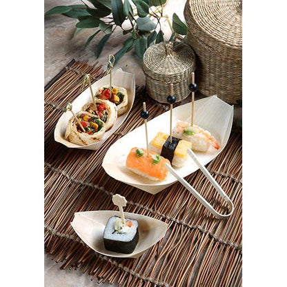 Finger food como sushi e wraps no espeto são servidos em 50 tigelas de finger food de madeira "pure" barquinhos da PAPSTAR GmbH sobre uma esteira de bambu com cestos e folhas verdes ao fundo.