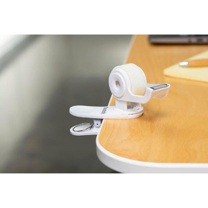 O dispensador de fita adesiva Scotch™ Clip & Twist C19 com fita adesiva invisível Scotch® Magic™ (19 mm × 8,89 m) da 3M Deutschland GmbH está preso a uma mesa de madeira ao lado de um bloco de notas e uma caneta.