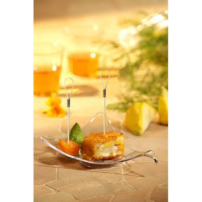 Close de um prato de aperitivos com dois snacks em tamanho de mordida em PAPSTAR 100 Fingerfood - Picker da PAPSTAR GmbH, feitos de bambu e guarnecidos com frutas, sobre uma superfície bege com bebidas e ervas ao fundo.