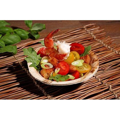 Delicie-se com camarões, tomates cereja, croutons, rúcula e cebolinhas numa PAPSTAR GmbH Prato redondo «pure» em folha de palmeira (13 cm), ecológico — louça descartável sustentável perfeita para eventos que se preocupam com o ambiente.