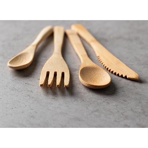 Quatro colheres de bambu PAPSTAR "pure" (16,5 cm, ecológicas e estáveis) estão lado a lado sobre uma superfície cinza texturizada, oferecendo uma solução sustentável para a mesa da PAPSTAR GmbH.