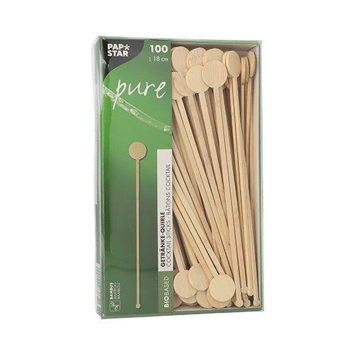 Uma caixa com 100 PAPSTAR GmbH "pure" misturadores de bebidas de bambu, biodegradáveis, com extremidades redondas e planas, parcialmente visíveis através de uma janela em embalagem verde e branca PAPSTAR Pure.