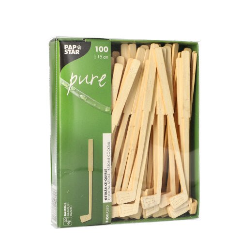 Uma caixa verde com a inscrição "PAPSTAR 100 misturadores de bebidas, bambu "pure" da PAPSTAR GmbH contém 100 palitos de mexer de bambu ecológicos (aprox. 15 cm), parcialmente visíveis através de uma janela. A caixa é decorada com texto branco e um gráfico de folha.