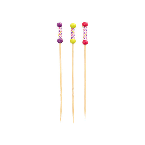 Três PAPSTAR 100 Fingerfood-Picker da PAPSTAR GmbH de bambu estão em pé. Cada palito tem uma alça decorativa com pérolas coloridas (roxa, amarela, rosa) e um padrão de cruz.