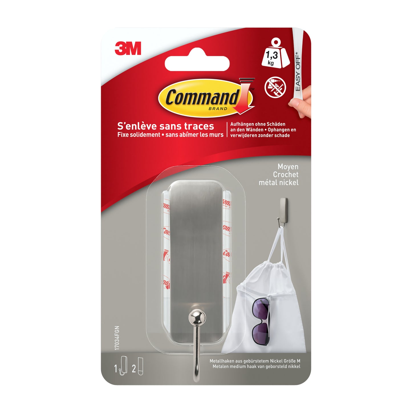 Der mittelgroße Command™ Metallhaken in gebürstetem Nickel (17034) von 3M Deutschland GmbH wird originalverpackt mit Haken und 2 Strips gezeigt. Die Tragkraft beträgt 1,3 kg, illustriert mit einer Tasche am Haken auf der Verpackung.